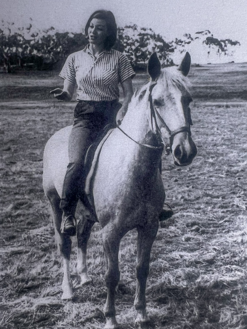 Black and white photo of a young woman on a white horse
