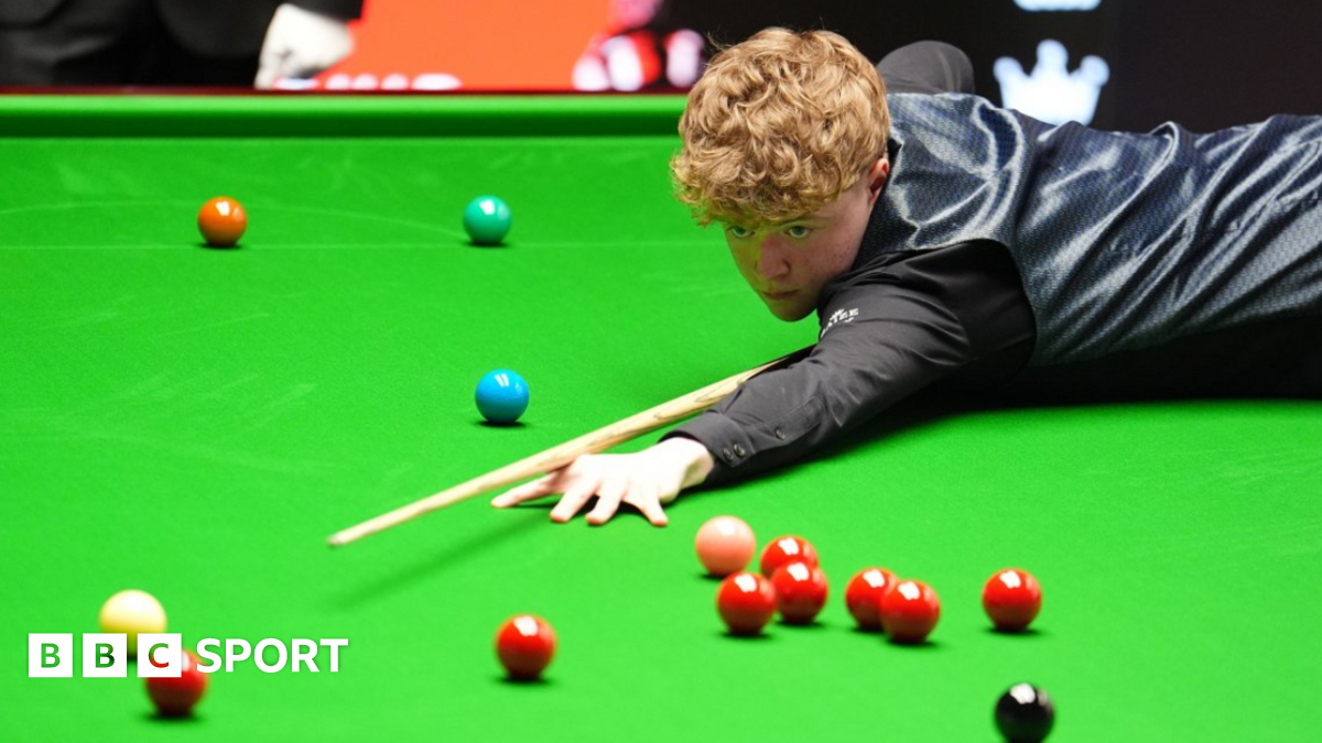 Stan Moody stretches over the snooker table to play a shot