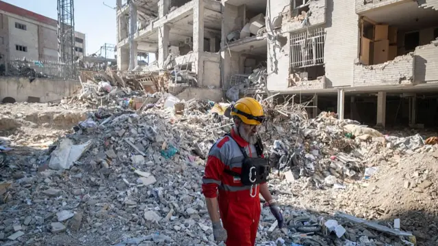 A rescue team member walks through the rubble of a building in Tehran