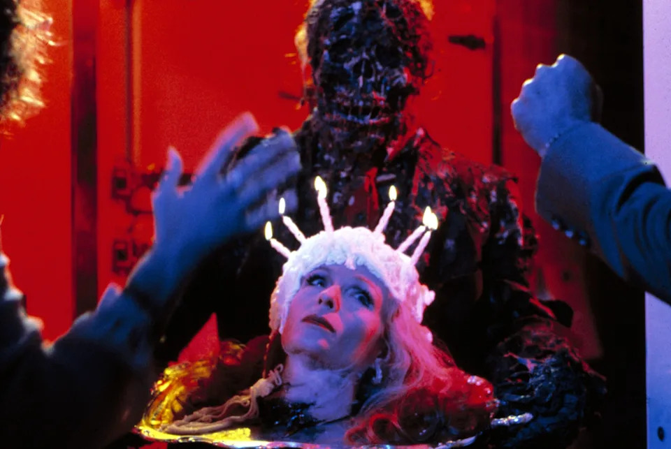 A person wearing a white headpiece with lit candles, surrounded by figures in a dramatic scene