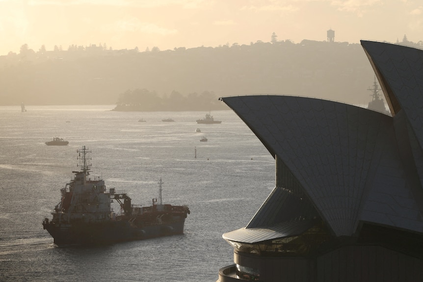 An oil products tanker passes the Sydney Opera House at sunrise.