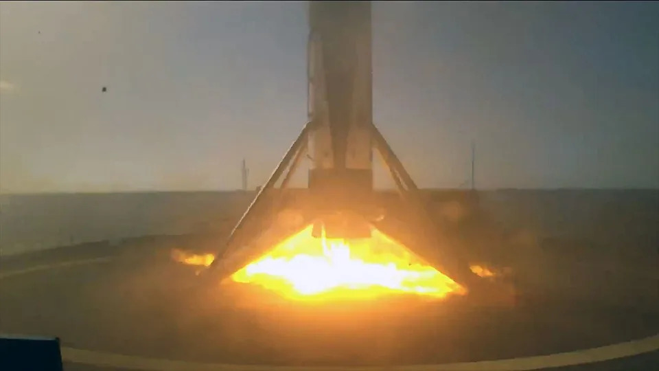 A rocket standing on its four landing legs just before engine cutoff atop an ocean-based droneship.