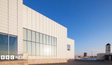 The image shows the outside of an art gallery against a deep blue sky.