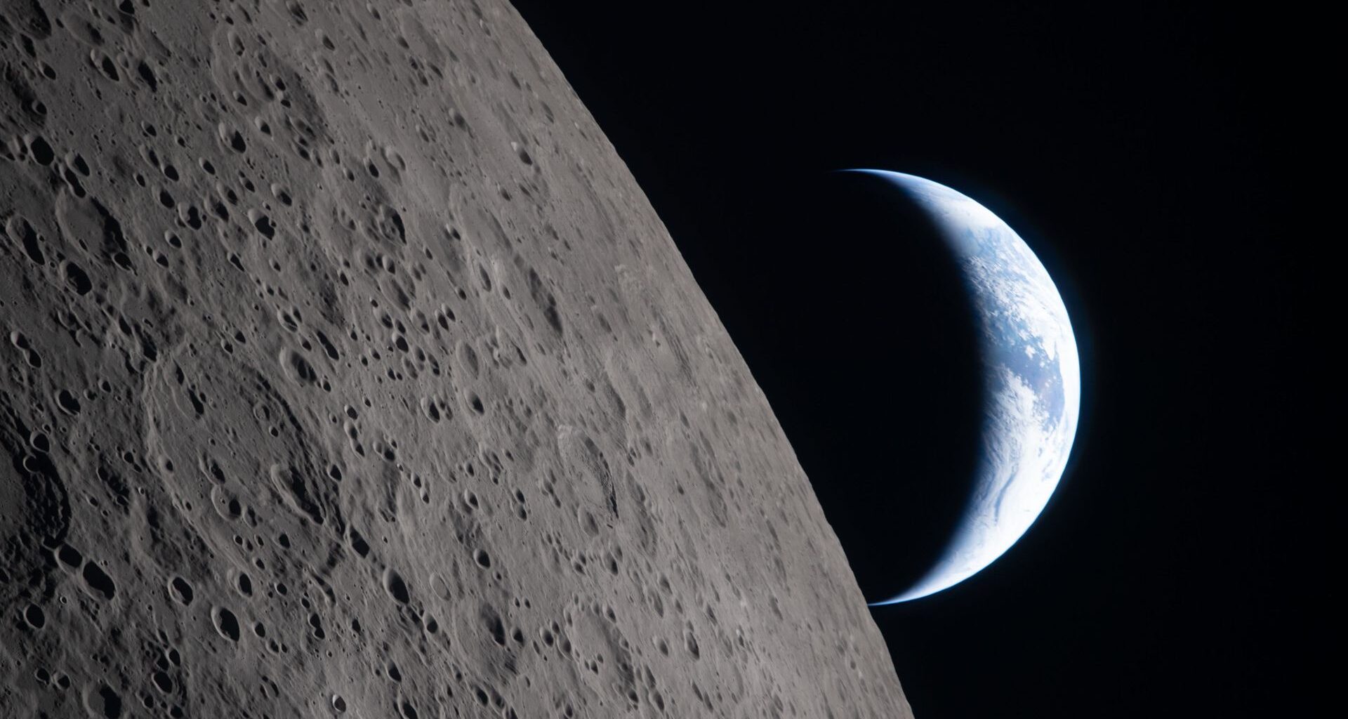 A view of Earth from the moon, with half the Earth illuminated and the gray surface of the moon in the foreground.
