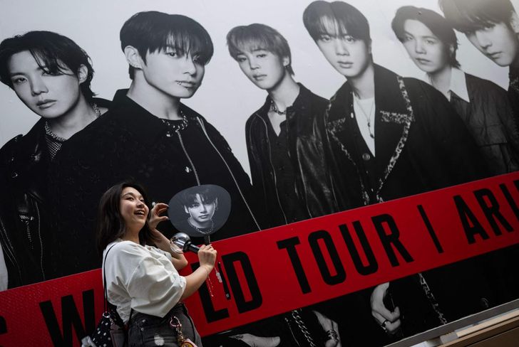 A fan of BTS poses in front of a poster at Tokyo Dome before the start of the K-pop band's tour in Tokyo, April 17. AFP-Yonhap