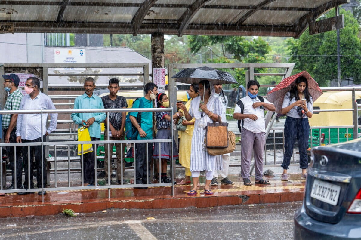 People wait for public transport in the rain in New Delhi. Daily decisions are influenced less by conviction and more by convenience, price, habit, time and the actions of others. For example, some urban transit systems have made digital ticketing and integrated mobility cards the default, subtly encouraging public transport use. (AP Photo/Rajesh Kumar Singh)