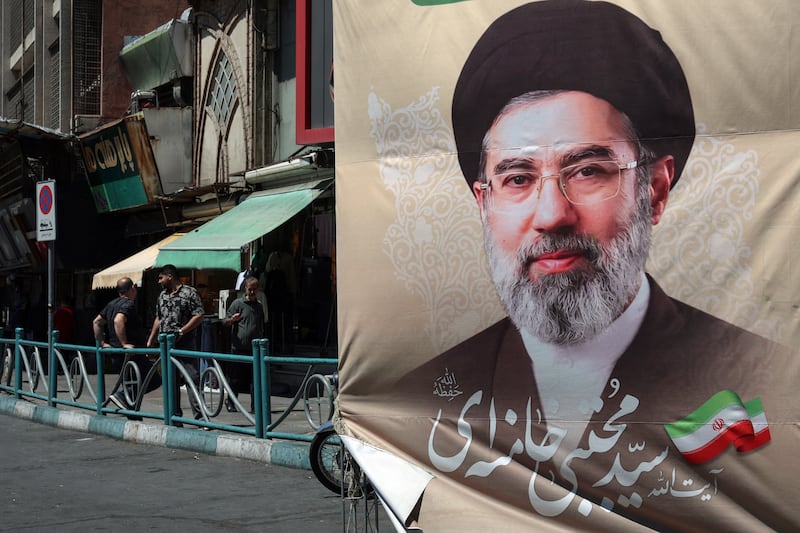 Iranians stand on a pavement along a street next to a billboard depicting Iran's Supreme Leader Ayatollah Mojtaba Khamenei, in Tehran on April 24, 2026. (Photo by AFP via Getty Images) / 