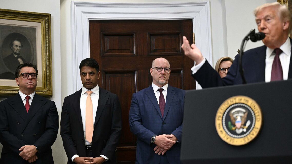 Four pharmaceutical executives, including Merck CEO Robert Davis, stand behind US President Donald Trump, who is speaking at a podium in the White House.