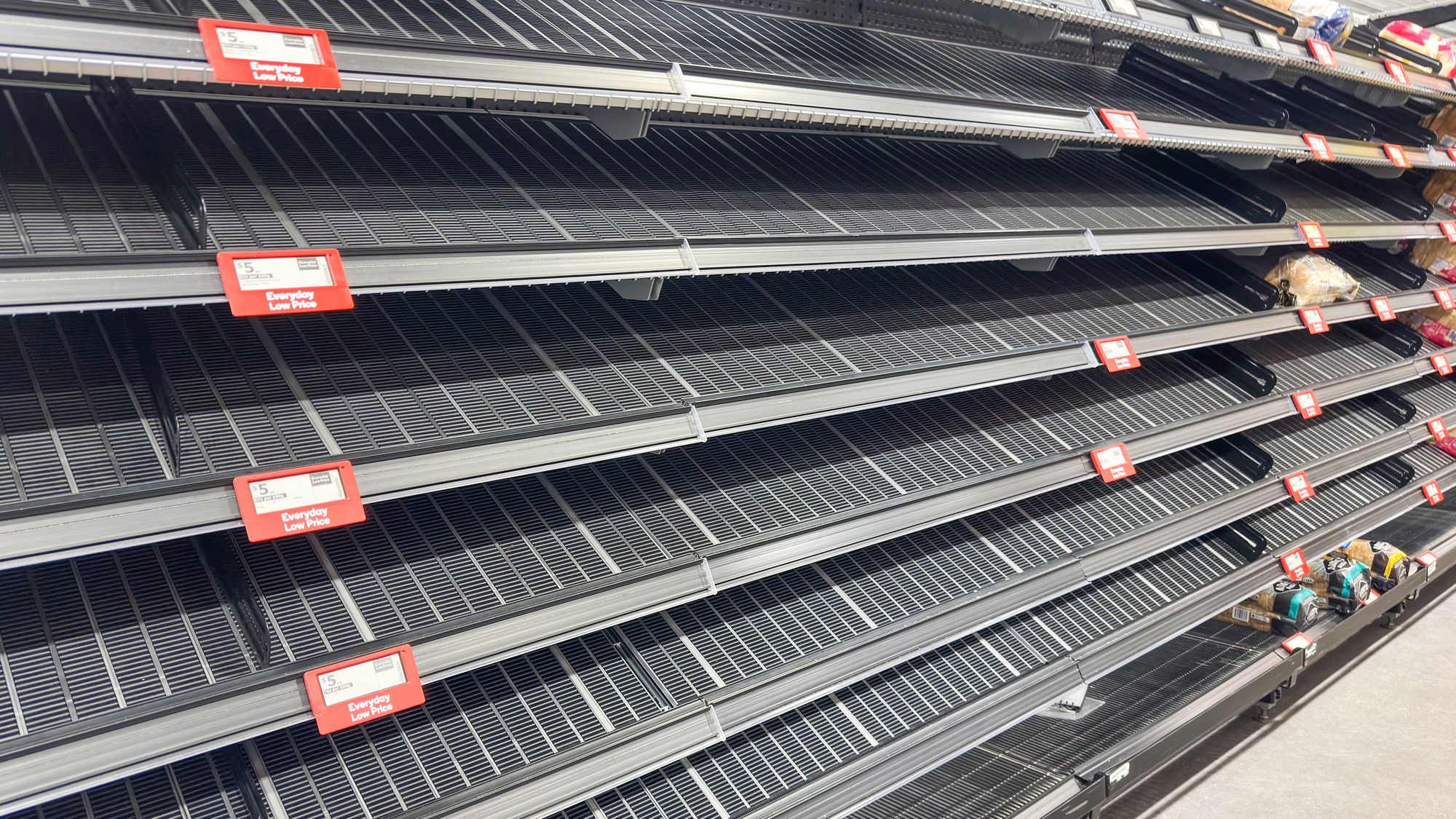 photograph of empty shelves with a couple of items of bread remaining.