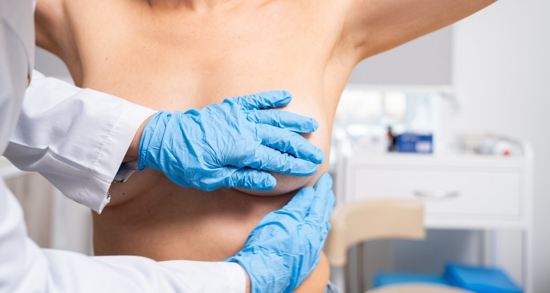 A doctor performs a breast examination on a female patient in a medical setting.