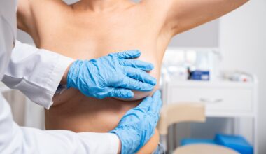 A doctor performs a breast examination on a female patient in a medical setting.