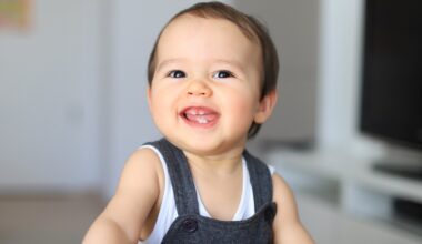 Headshot portrait of cute smiling baby with first milk teeth. Mixed race Asian-German infant laugh and having fun at home. Happy and healthy child about 9-10 months old.