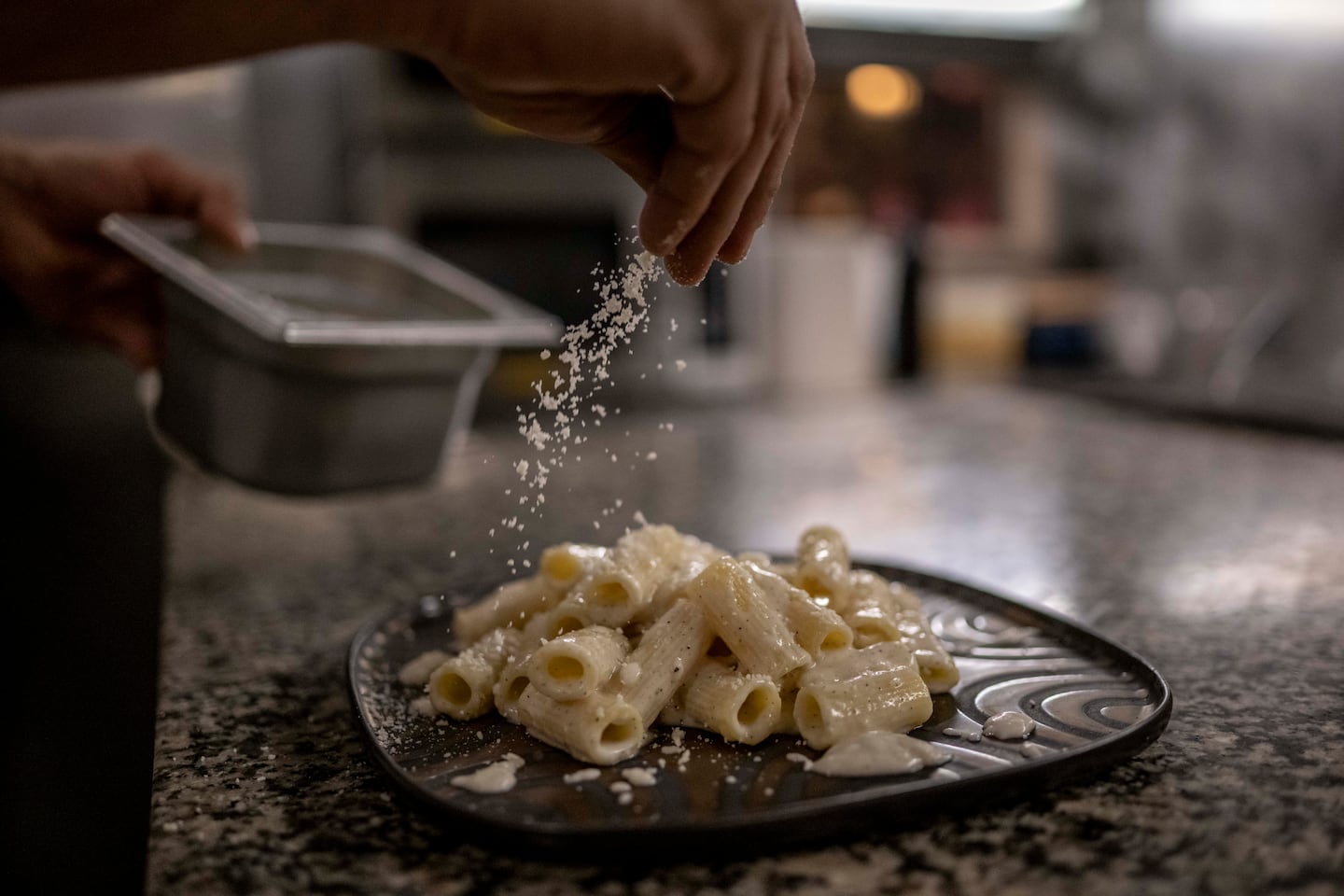 Chef Giuseppe Bello puts Parmigiano cheese on the pasta "Gricia" during dinner at Saltimbocca restaurant.