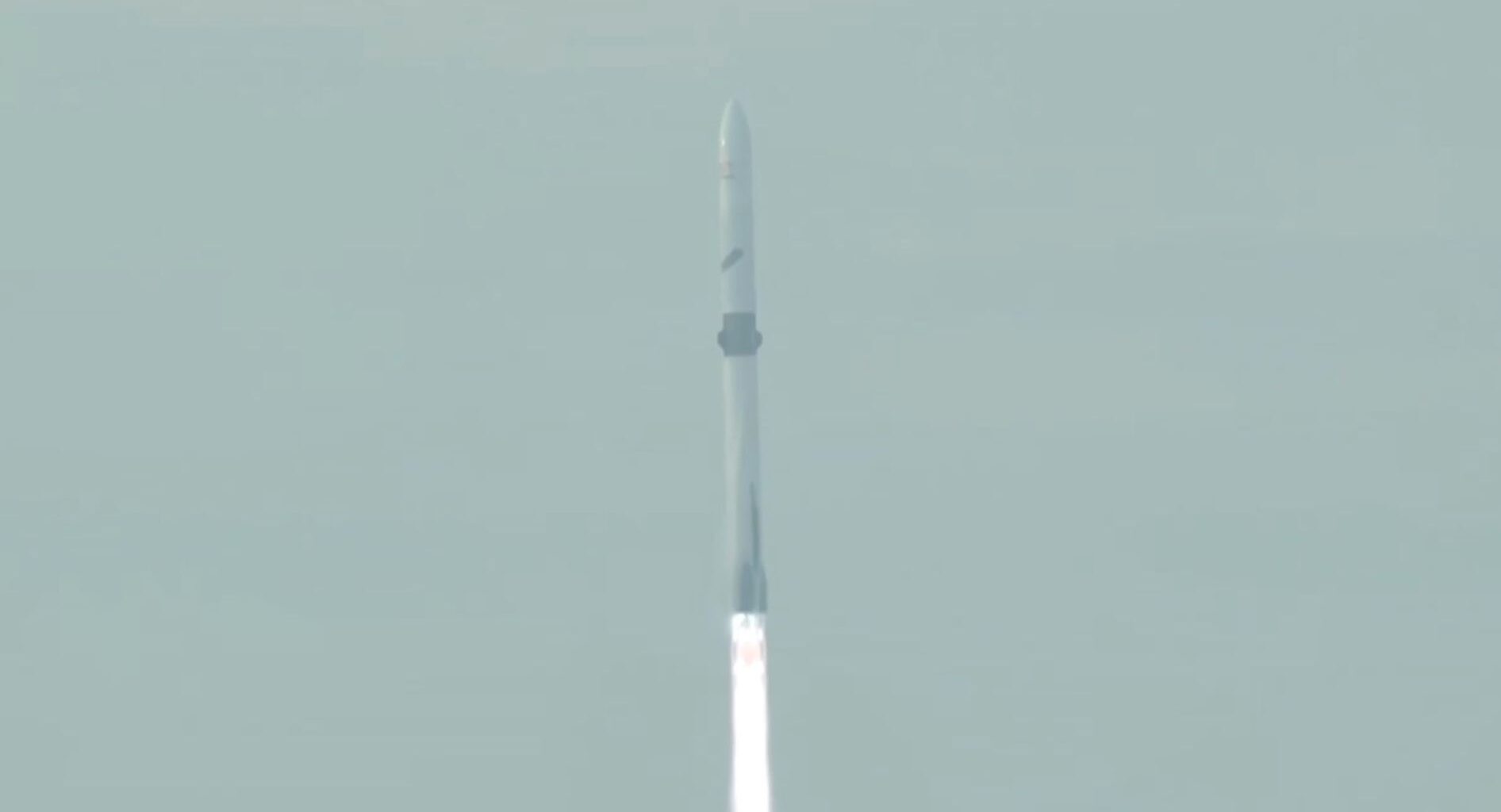 closeup of a white rocket rising into a hazy sky