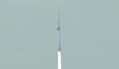 closeup of a white rocket rising into a hazy sky