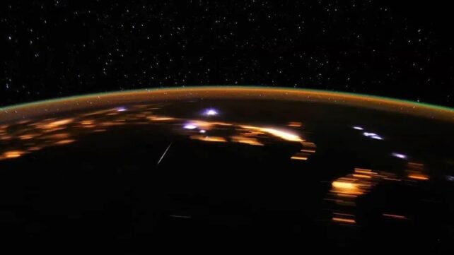 A view from space of Earth at night with meteors appearing as bright lights across the surface