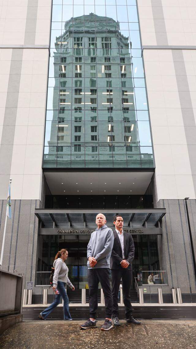 Pablo Langesfeld, left, who lost his daughter and son-in-law in the 2021 Champlain Towers collapse, stands with his son Martin, right, outside the Osvaldo N. Soto Miami-Dade Justice Center in Miami, Tuesday, April 7, 2026. Langesfeld, now battling advanced pancreatic cancer, is suing Oscar Health Insurance for denying coverage of a drug therapy his doctors recommend, underscoring broader struggles over access to treatment.