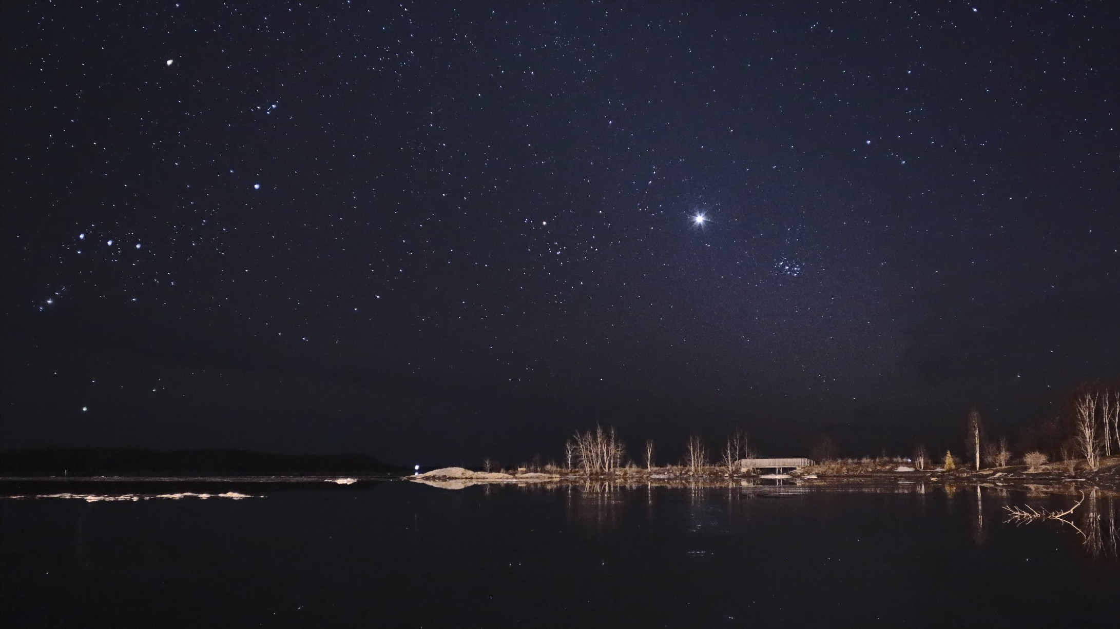 a starry night above a lake scene with Venus shining bright next to the Pleiades star cluster
