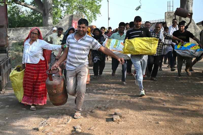 People carrying empty LPG (liquefied petroleum gas) cylinders run to stand in a queue before buying refilled gas cylinders in a village on the outskirts of Jewar, India, on Friday. Photograph by Arun Sankar/AFP via Getty Images