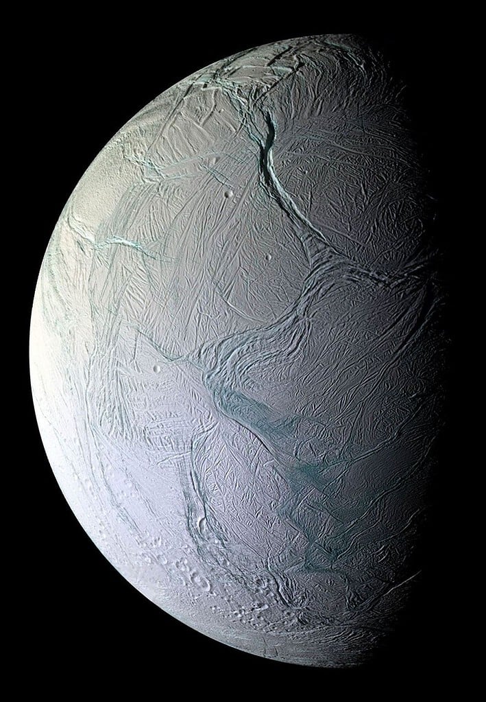 Ice-covered moon with surface cracks and icy terrain. Enceladus.