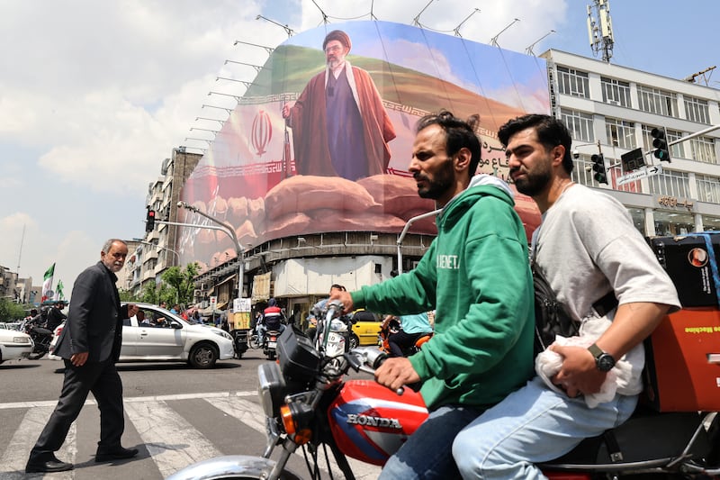 Iranians ride past a large billboard depicting Iran's supreme leader Ayatollah Mojtaba Khamenei on Monday. Photograph: Atta  Kenare/AFP/Getty Images 
