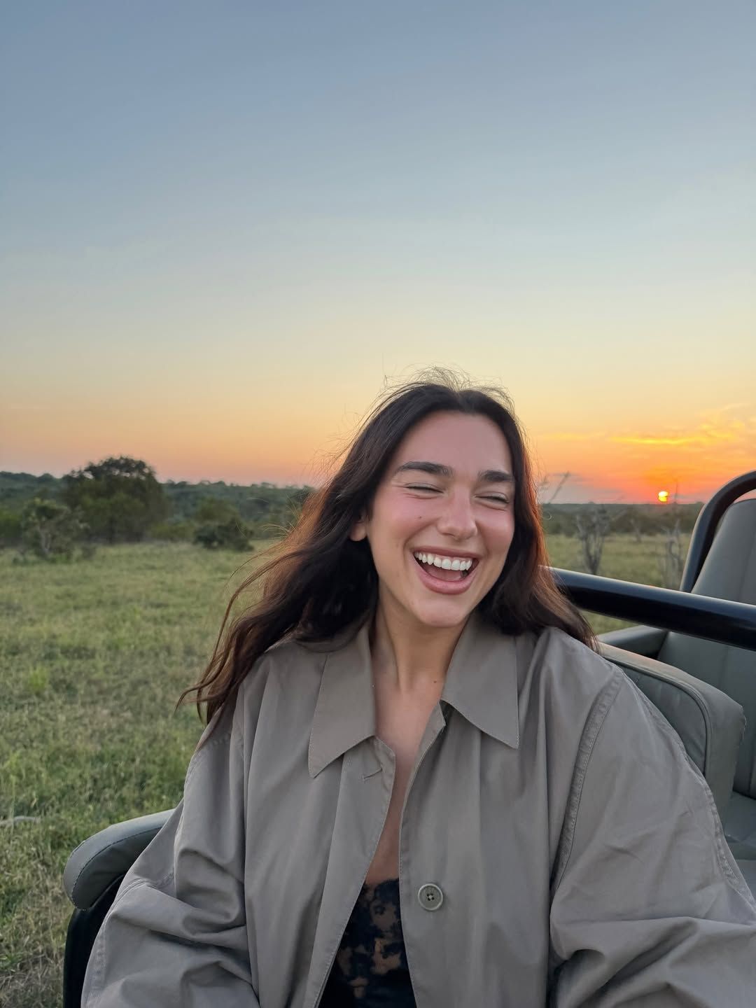 Image may contain Dua Lipa Face Head Person Happy Laughing Adult Smile Clothing and Coat