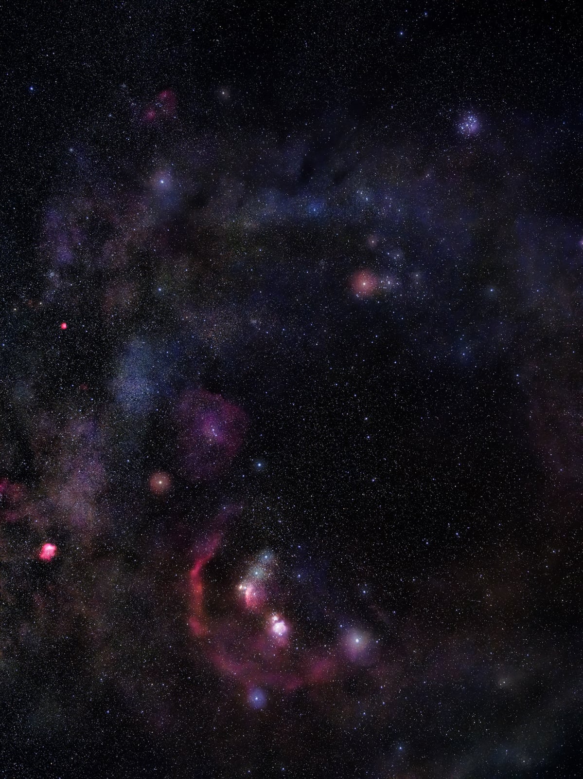 A vivid night sky shows a dense star field with colorful nebulas and clouds of interstellar dust, glowing in shades of red, blue, and purple against the dark backdrop of space.