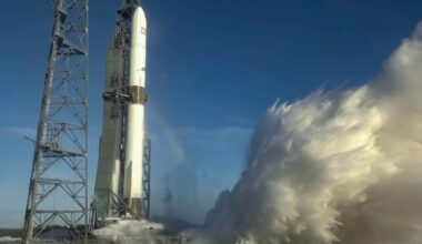 a large white rocket conducts an engine test on the pad beneath a blue sky