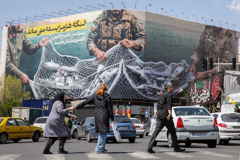 People walk in front of a billboard depicting captured US aircraft in a net in Tehran, Iran. Photograph: Arash Khamooshi/the New York Times
                      