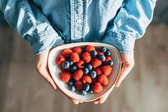 A woman holds a plate of fruits and berries in her hands A woman holds a plate of fruits and berries in her hands