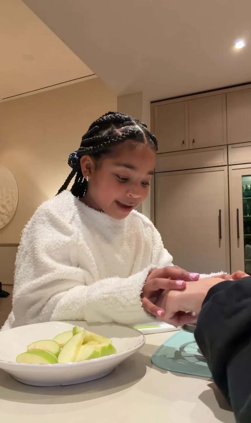 True holding hands with Khloé at a table with sliced apples