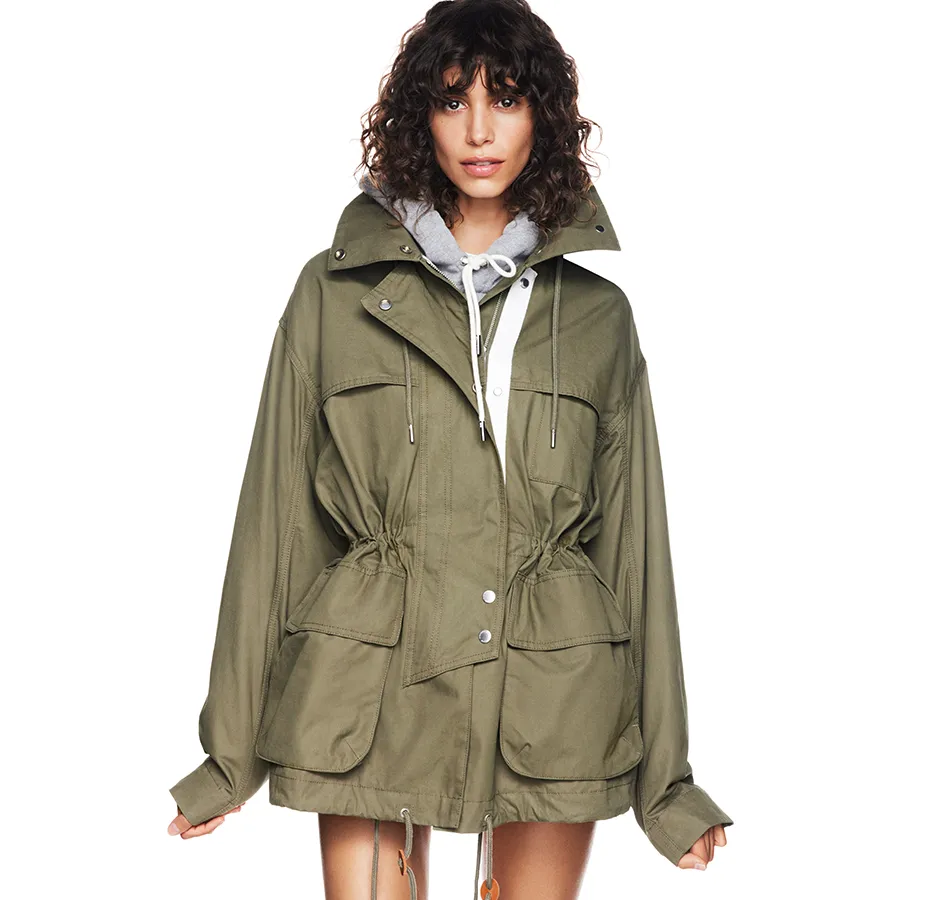 A woman wearing an olive green parka with a gray hooded sweatshirt underneath.