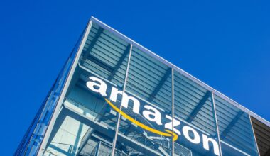 Amazon logo seen on a tall glass building under a blue sky.