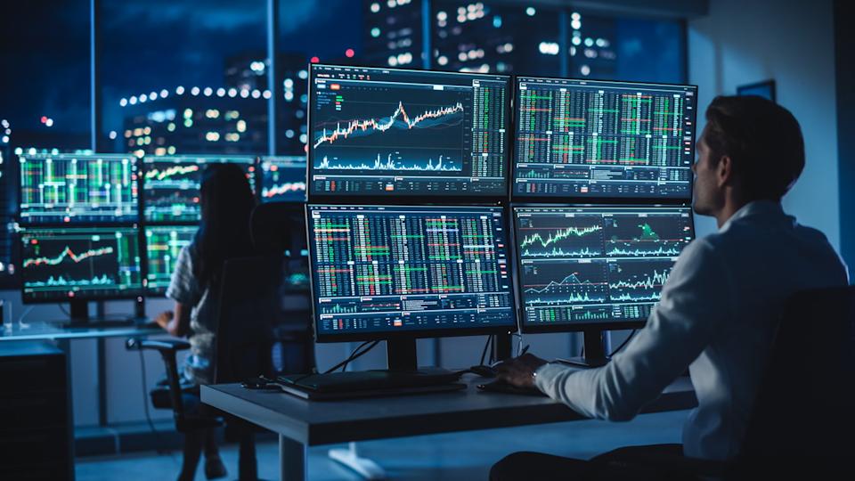 A financial analyst sitting at a desk studying stock chart movements.