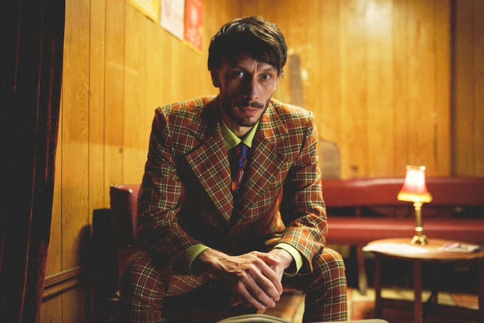 Donny sat down, leaning slightly forward, dressed in a suit