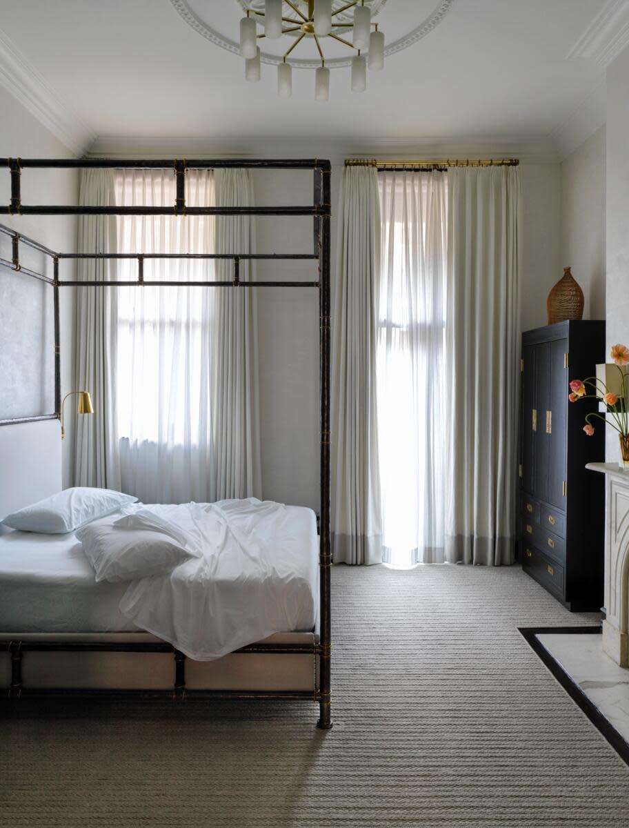 Minimalist bedroom with a four-poster bed and natural light.