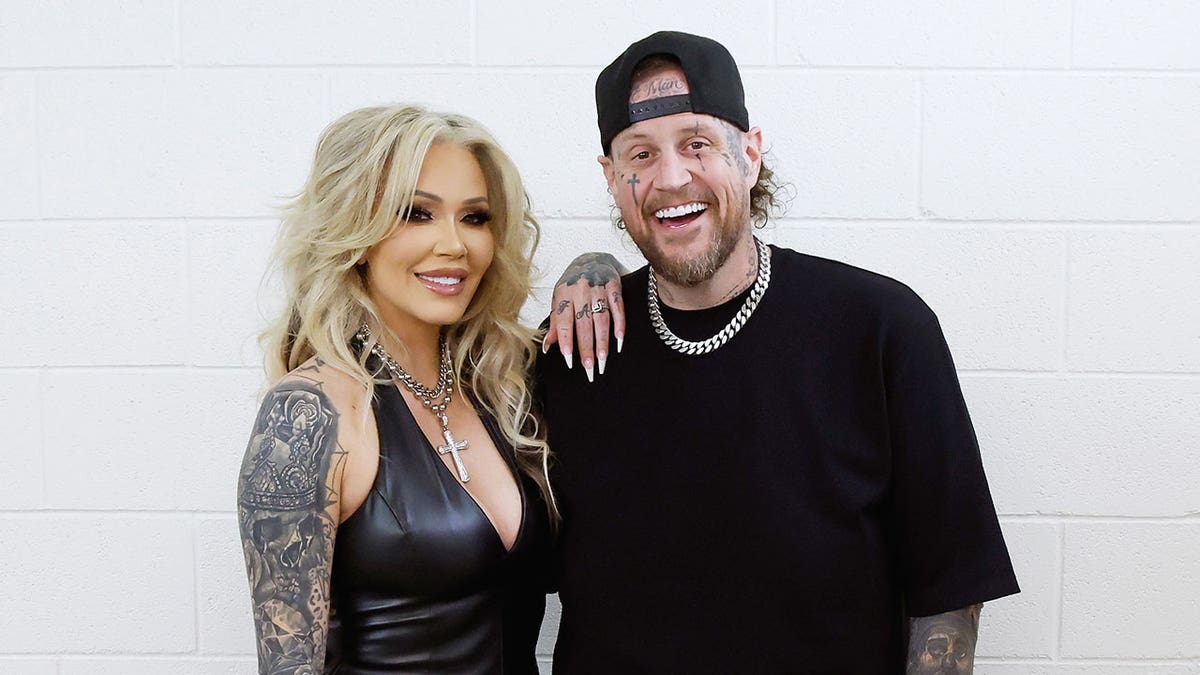 Bunnie Xo and her husband Jelly Roll posing and smiling for a portrait in matching black fashion.