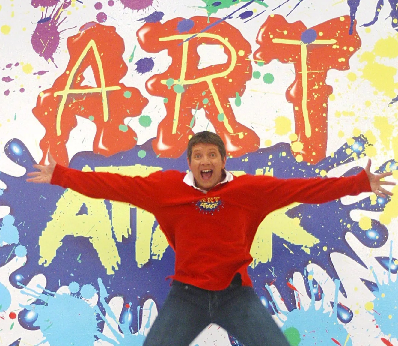 Neil Buchanan jumping in front of an "Art Attack" background.