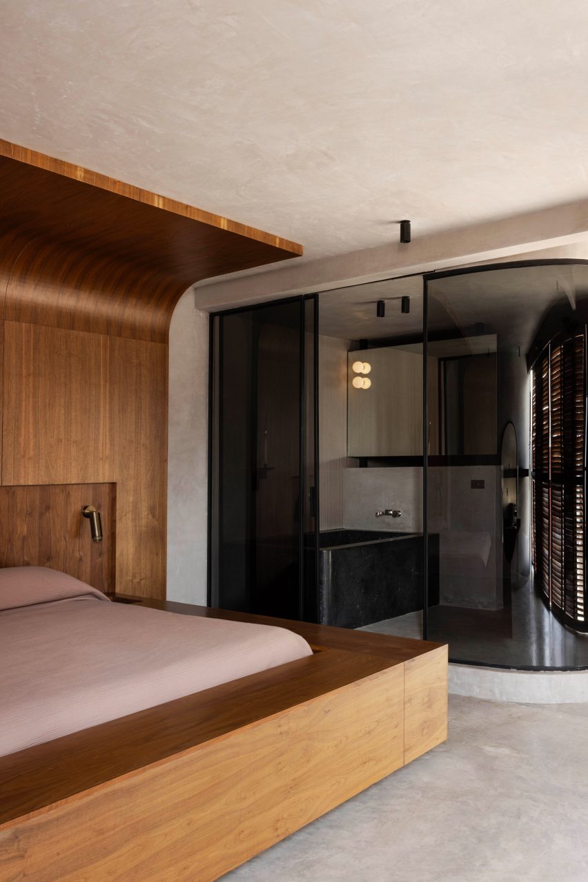 Dark-tinted glass curves around an en-suite bathroom