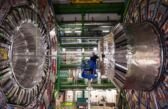 A person, center, right, is dwarfed by the size of the CMS experiment at the Large Hadron Collider, shown here in 2024. Credit: CMS/CERN