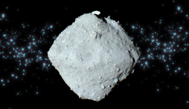 A gray top-shaped space rock with a swarm of light blue dots behind it.