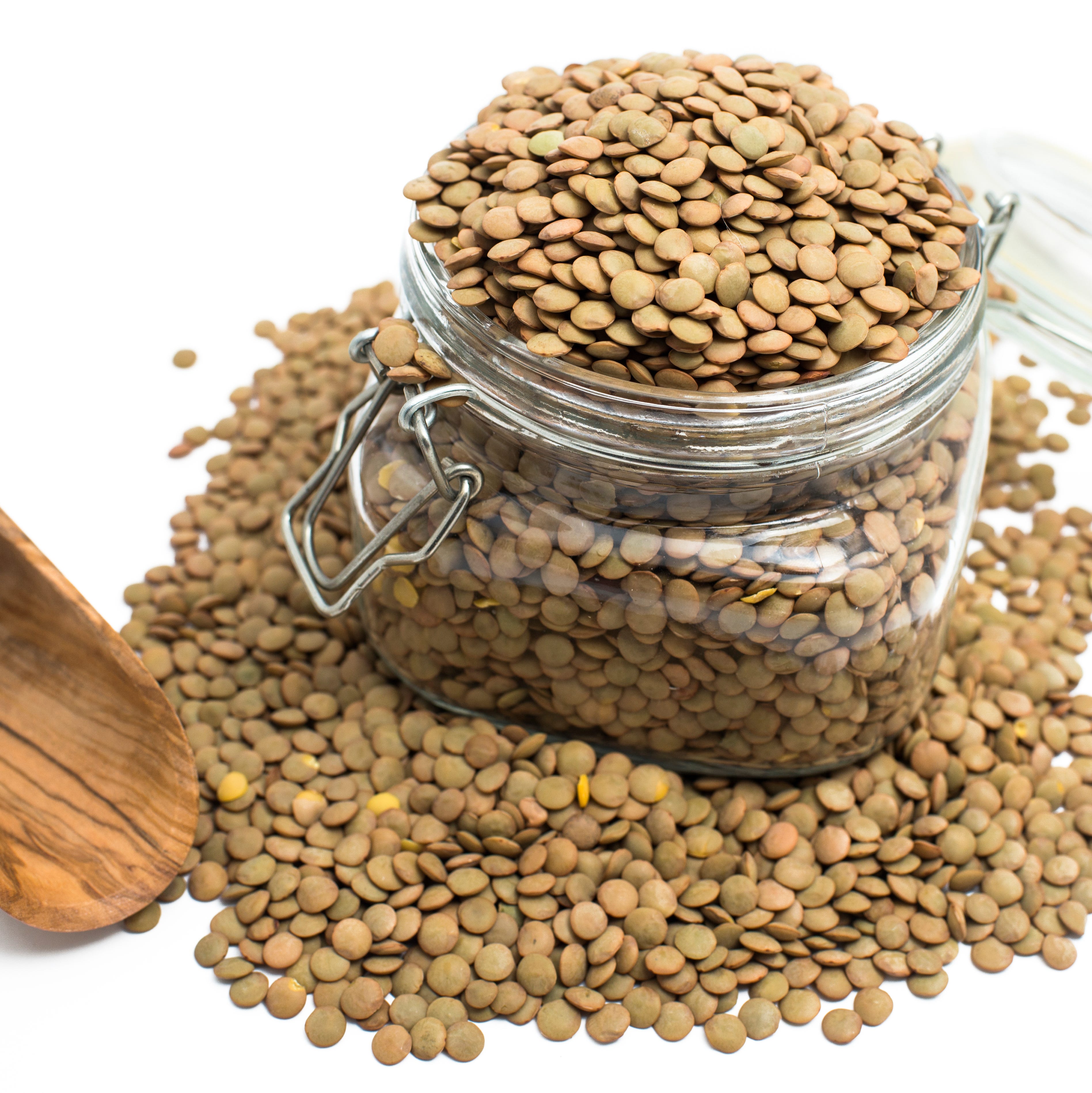 Raw lentils and wooden spoon on white background
