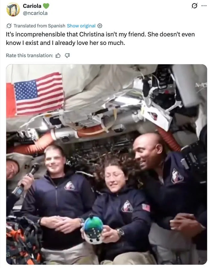 Astronauts float in a space station, smiling and holding a small globe. An American flag is visible in the background