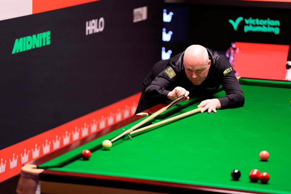 John Higgins uses the rest to reach a red. Photo: PA