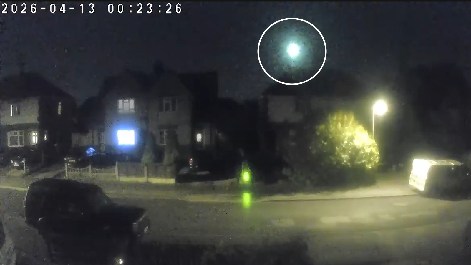 Screenshot of a doorbell recording showing a bright green flash of light in the night sky above a house