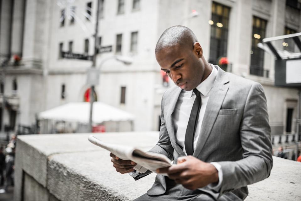 A Wall Street trader reading the newspaper outside.