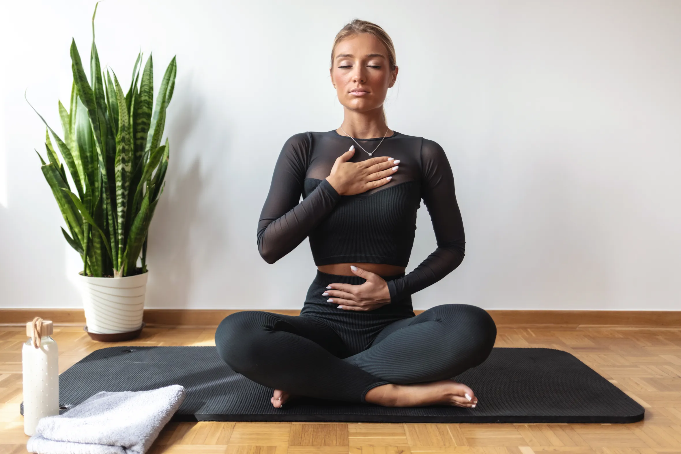 Woman with eyes closed in a yoga pose, using Pranayama breathing technique.
