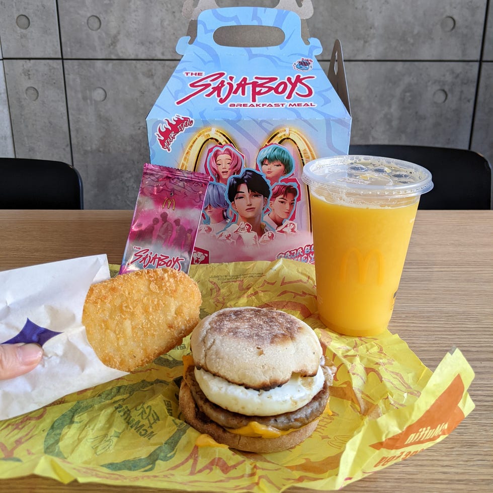 Breakfast meal including a sandwich, hash brown, drink, and themed packaging.