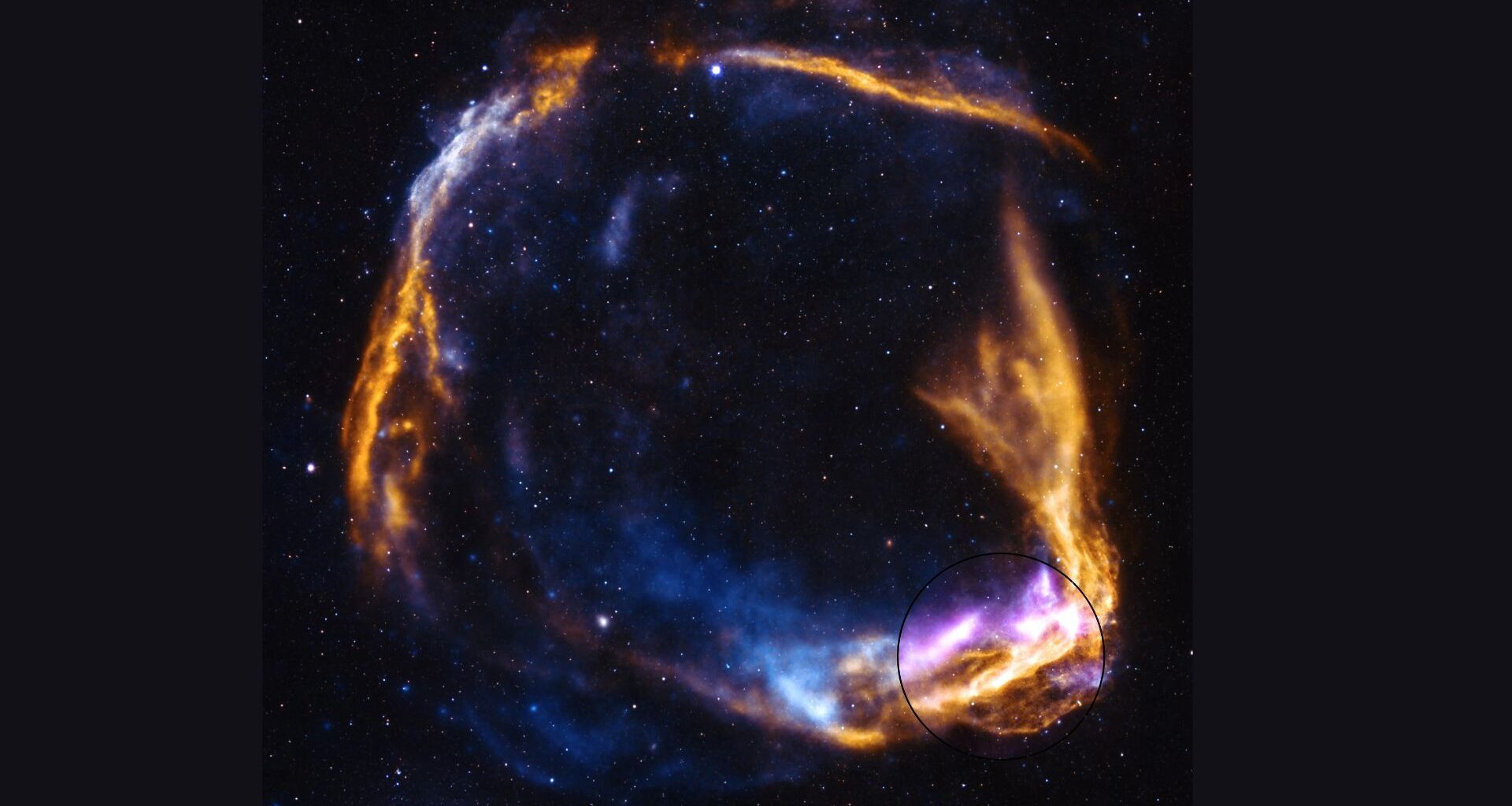 A circular array of blue and pink and orange gas swirls against a dark starry background