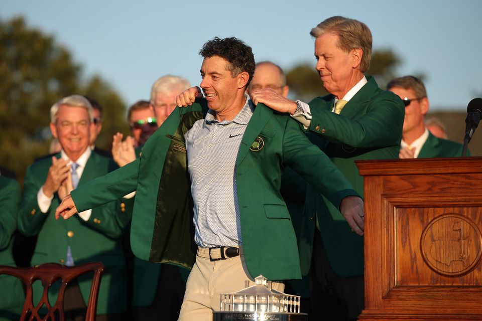 Rory McIlroy is presented with with the green jacket after retaining his Masters title at Augusta National